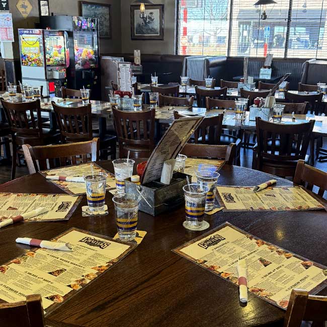 Tables at this restaurant in Monticello MN are set with menus, glasses, silverware, and chairs.