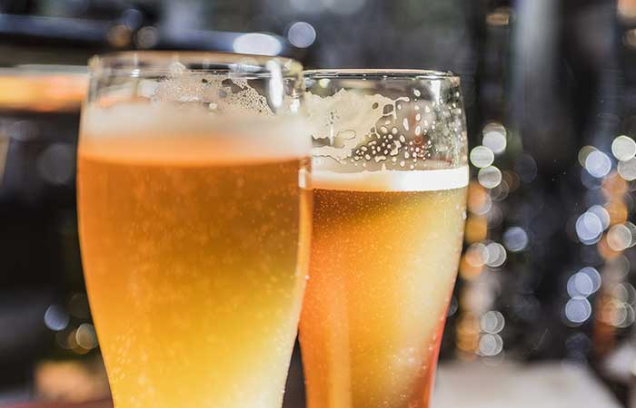 Two tall beers with foam, perfect for your next night out—see our bar menu in Monticello MN!.