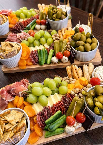 Three wooden platters showcase catering in Monticello MN with cheeses, meats, and fresh vegetables.