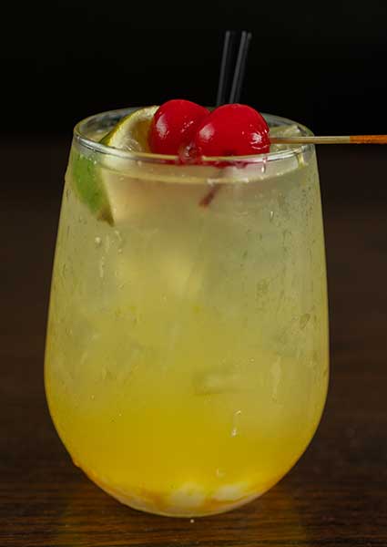 Signature yellow cocktail at a restaurant in Monticello MN, garnished with lime and cherries.