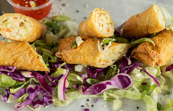 Crispy egg rolls on shredded lettuce at Monticello restaurant, served with dipping sauce in back.