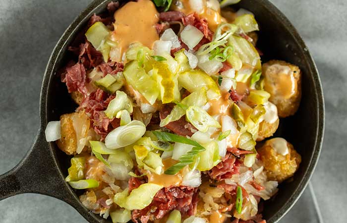Enjoy during happy hour Monticello MN: Tater tots with meat, onions, pickles, sauce, and greens.