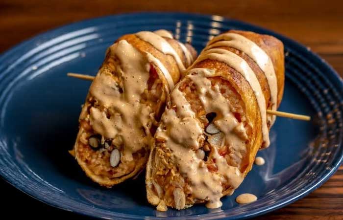Featured on our restaurant menu Monticello MN: two sliced taquitos with creamy sauce, blue plate.