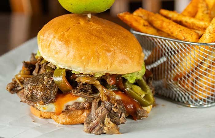 Juicy pulled beef sandwich with cheese, peppers, and fries at a restaurant in Monticello MN.